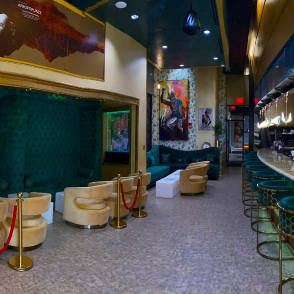 Aroma Restaurant & Lounge interior with teal velvet seating, gold accents, and a long bar with stools.