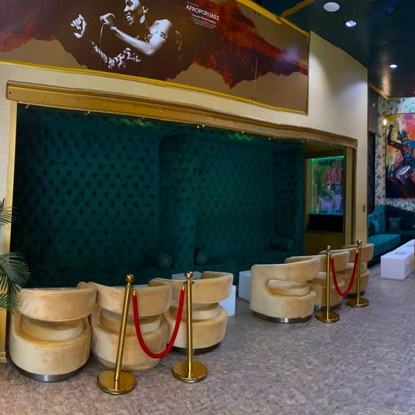 Aroma Restaurant & Lounge interior with plush green booths, gold chairs, and a large Afropop/Jazz mural.
