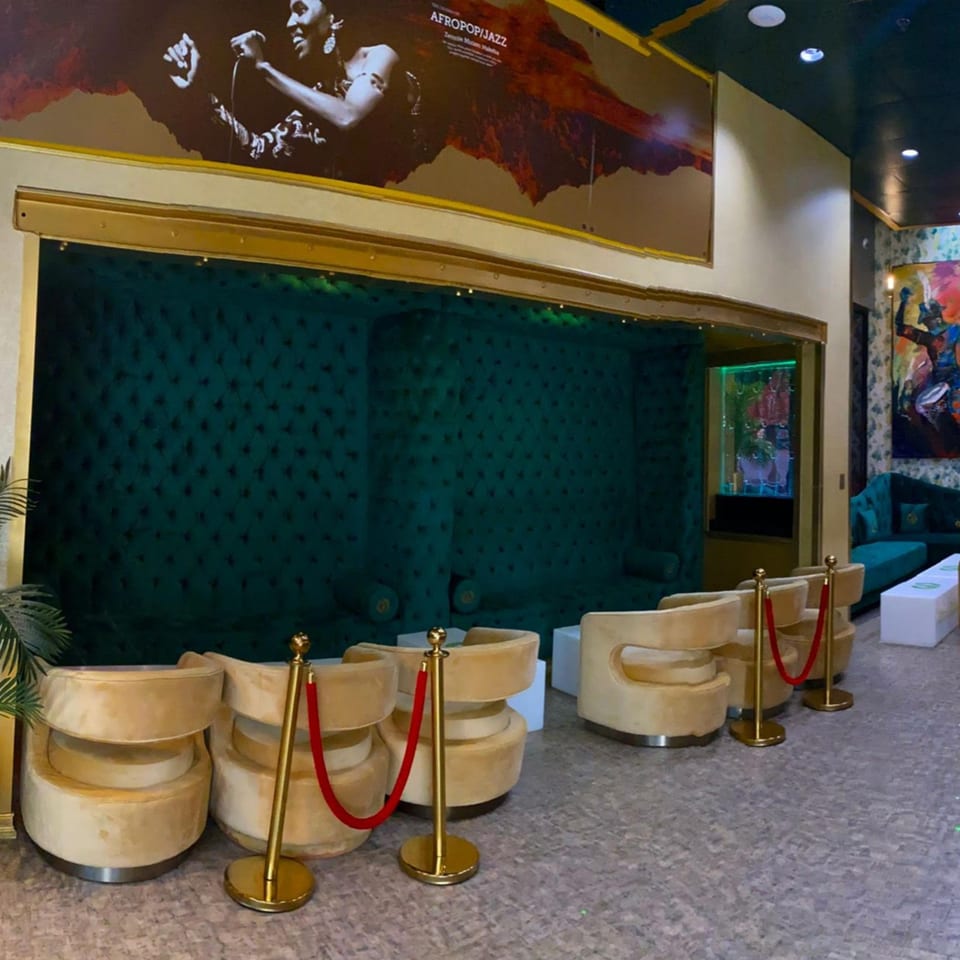 Aroma Restaurant & Lounge interior with plush green booths, gold chairs, and a large Afropop/Jazz mural.