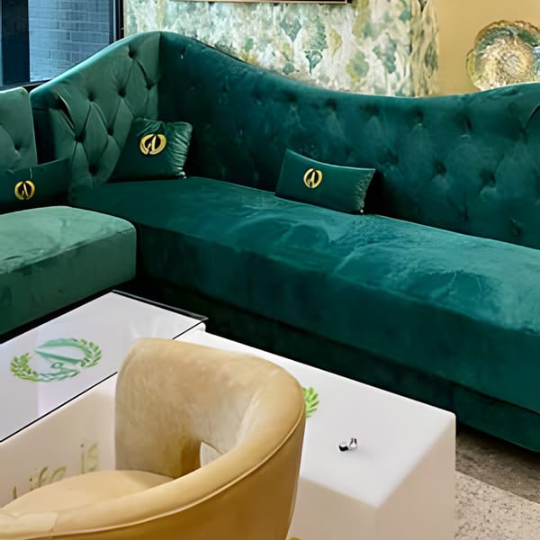 A luxurious green velvet sectional sofa with gold-accented pillows and a white coffee table.