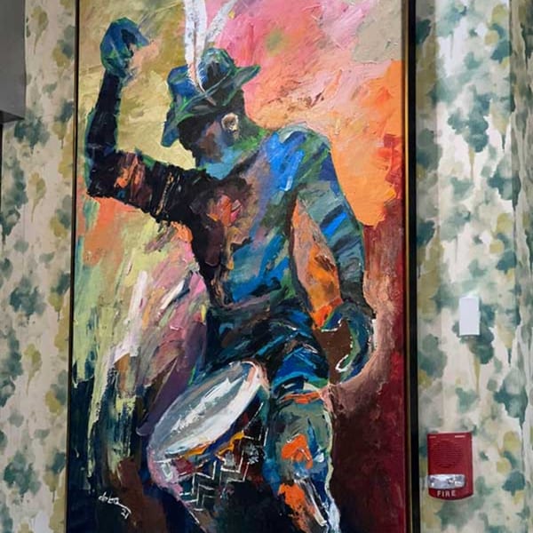 Abstract painting of a person in a hat playing a drum, in vibrant blues, oranges, and yellows.