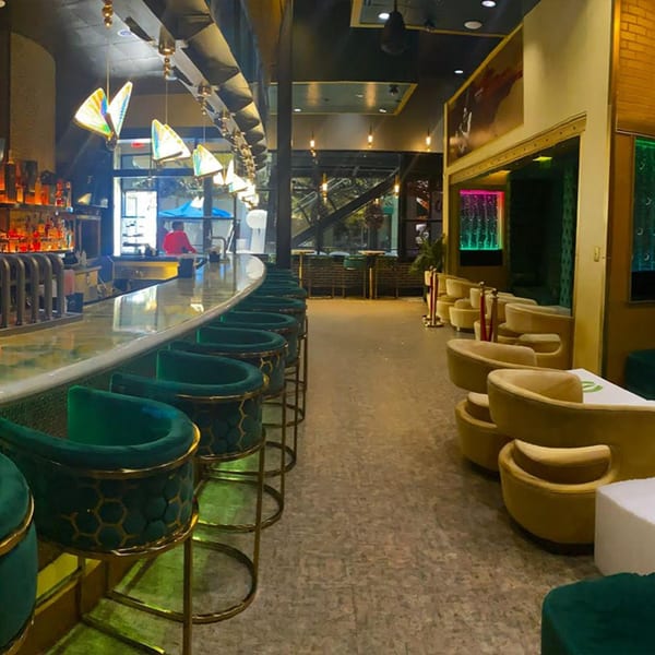 Aroma Restaurant & Lounge's bar area with green velvet bar stools and yellow lounge chairs.