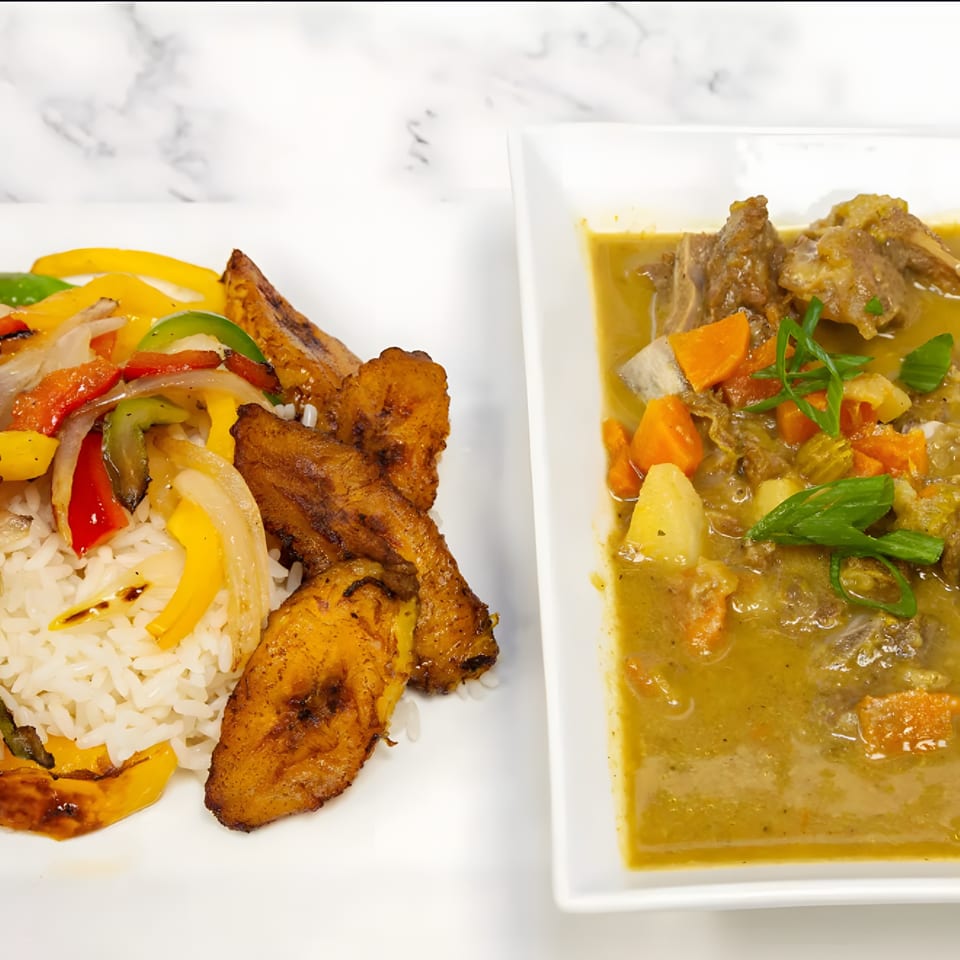 African curry with meat and vegetables, alongside rice, fried plantains, and sautéed peppers and onions.