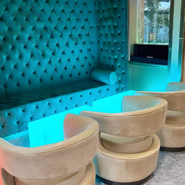 Aroma Restaurant & Lounge features a teal tufted booth, glowing blue table, and beige chairs.