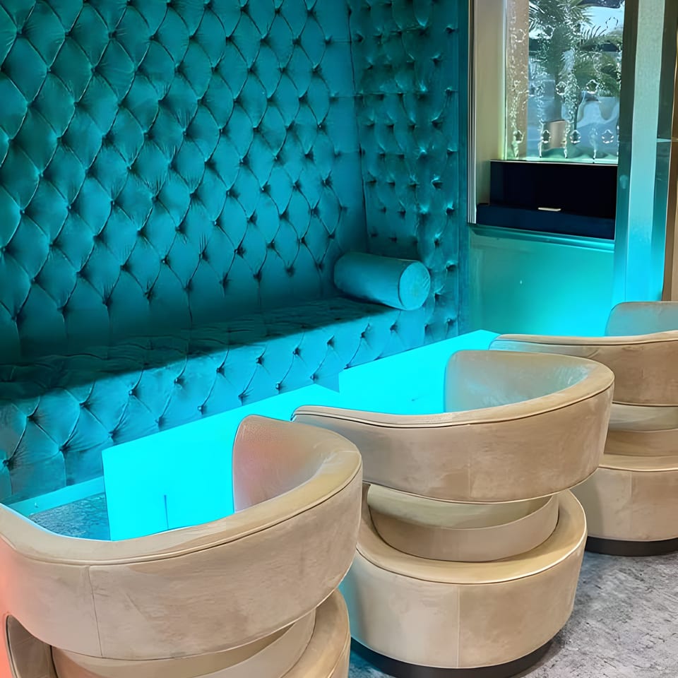 Aroma Restaurant & Lounge features a teal tufted booth, glowing blue table, and beige chairs.
