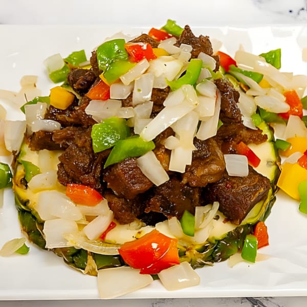 African beef stew with bell peppers and onions, served on a pineapple slice.